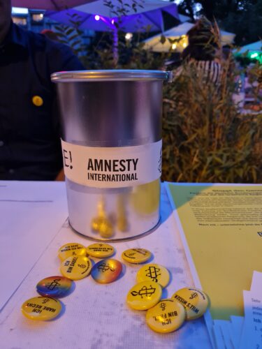 Amnesty Spendenbox mit Buttons auf einem Tisch