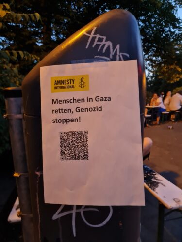Zettel mit QR Code für Genozid-Petition an Mülleimer