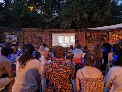 Menschen sitzen vor einem Screen in einem open-air-Kino